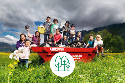 Viele Kinder sitzen in einem roten Zimmermann Container auf einer Wiese und posieren für ein Foto