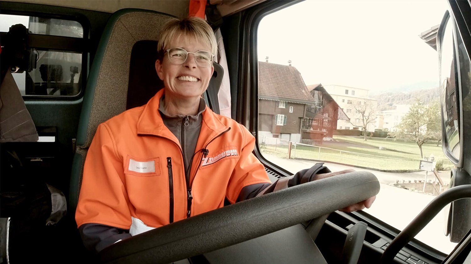 Frau in orangener Kacke sitz am Lenkrad einen Elektro-LKW